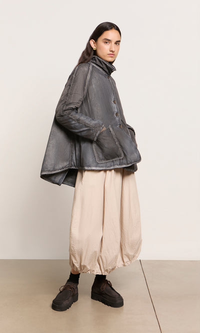 Plümo  Person in a Black Pepper Jacket and beige balloon pants stands on a light floor with neutral background.