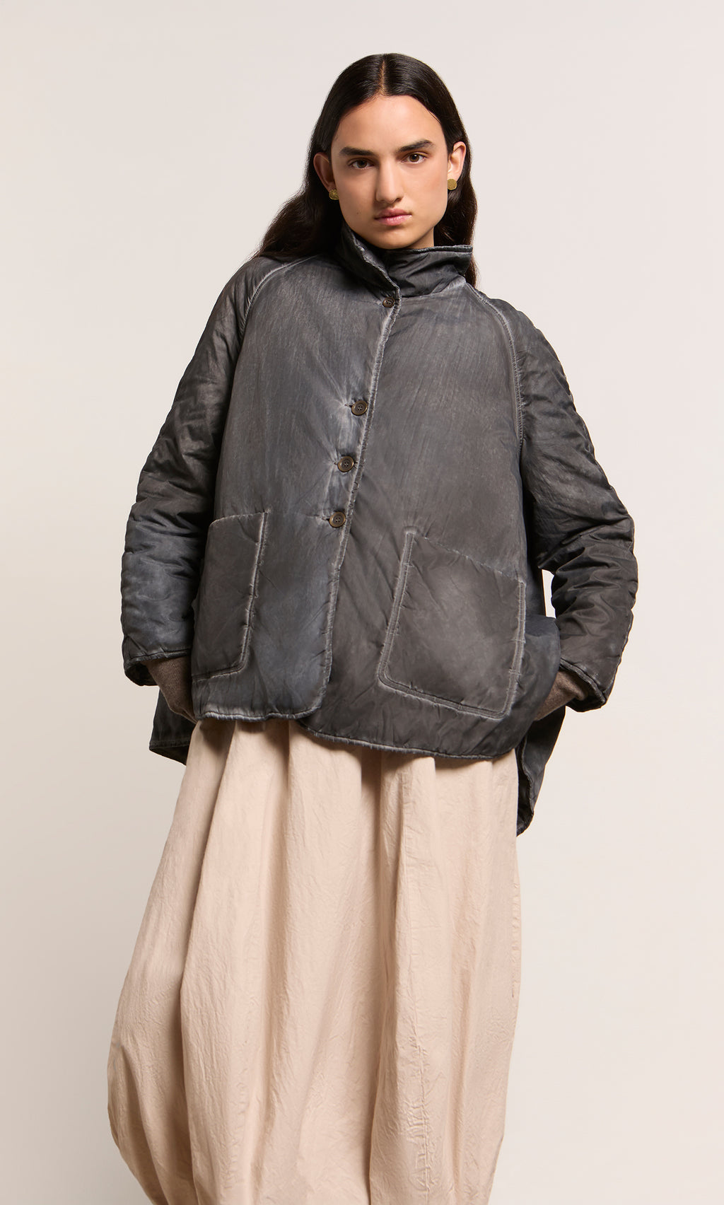 Plümo  Person wearing a Black Pepper Jacket with large pockets and a beige skirt, standing against a plain background.