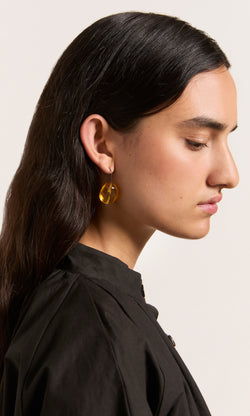 Plümo  Profile of woman with long dark hair wearing Amber Glass Earrings, featuring lightweight, amber-toned stones.
