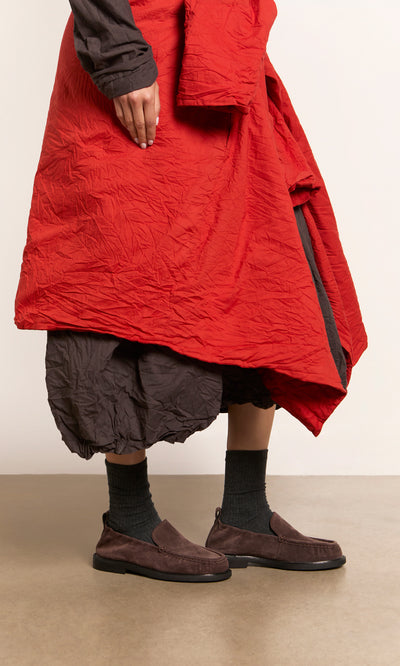 Plümo  Person in a red and brown crinkled dress wears Dobin Loafers, standing on a beige floor.