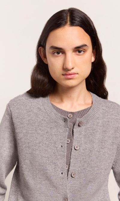 Plümo  Person with long dark hair wears the Grey Melange Cardigan, looking at the camera against a plain background.