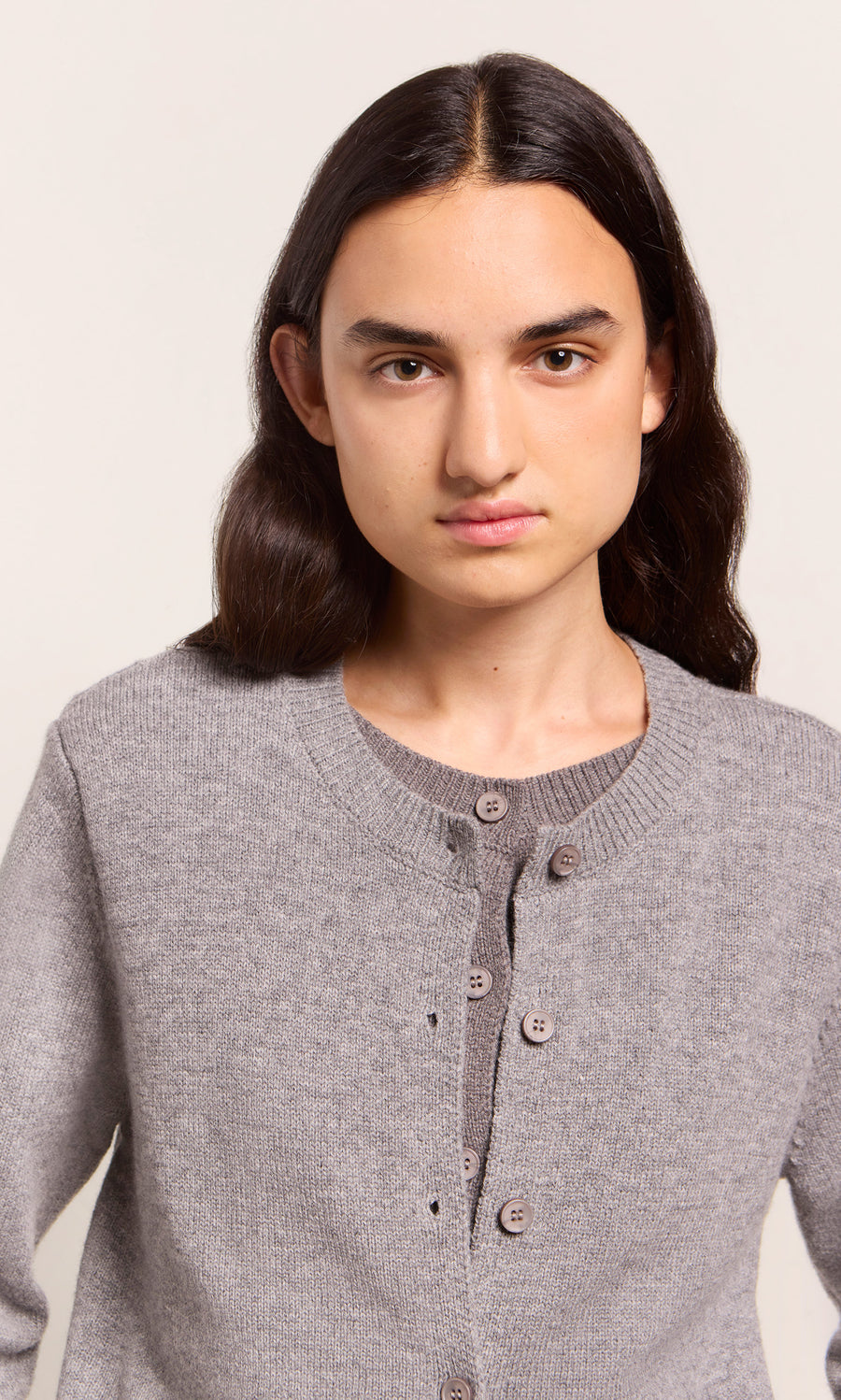 Plümo  Person with long dark hair wears the Grey Melange Cardigan, looking at the camera against a plain background.