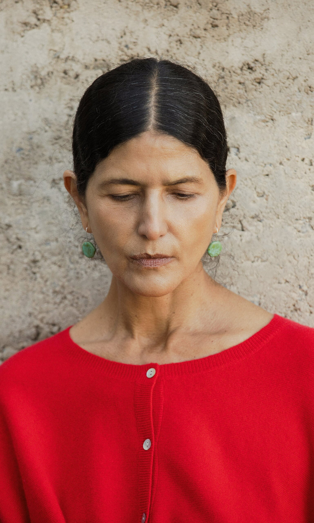 Plümo- Woman with dark hair, eyes closed, wears Erika Earrings—handcrafted marbled turquoise resin—by a stone wall in Cornwall.