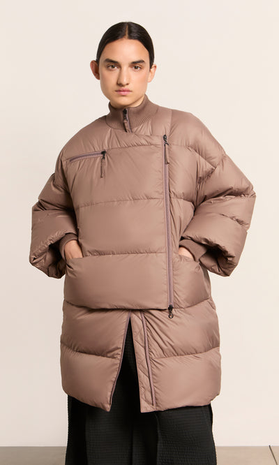 Plümo  Model wears the Firth Puffer Coat, featuring front zippers and classic Danish style, on a plain light background.