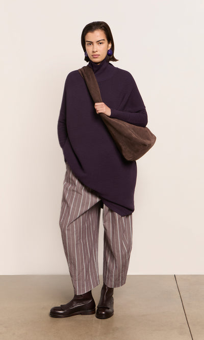 Plümo  Person in a Longer Jack Rollneck - Lupin, striped pants, and brown boots stands against a light background.