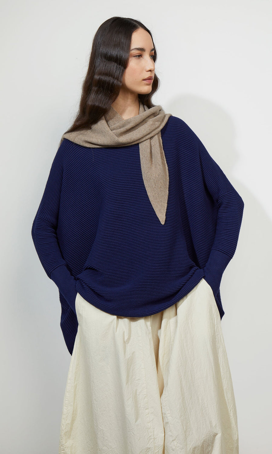 Plümo- Woman in the Jack Sweater - Navy, with dropped shoulders, cream skirt, and scarf, standing against a white background.
