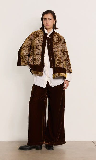 Plümo  Person in a patterned brown Kemsley Jacket, white shirt, brown pants, and black shoes against a plain background.
