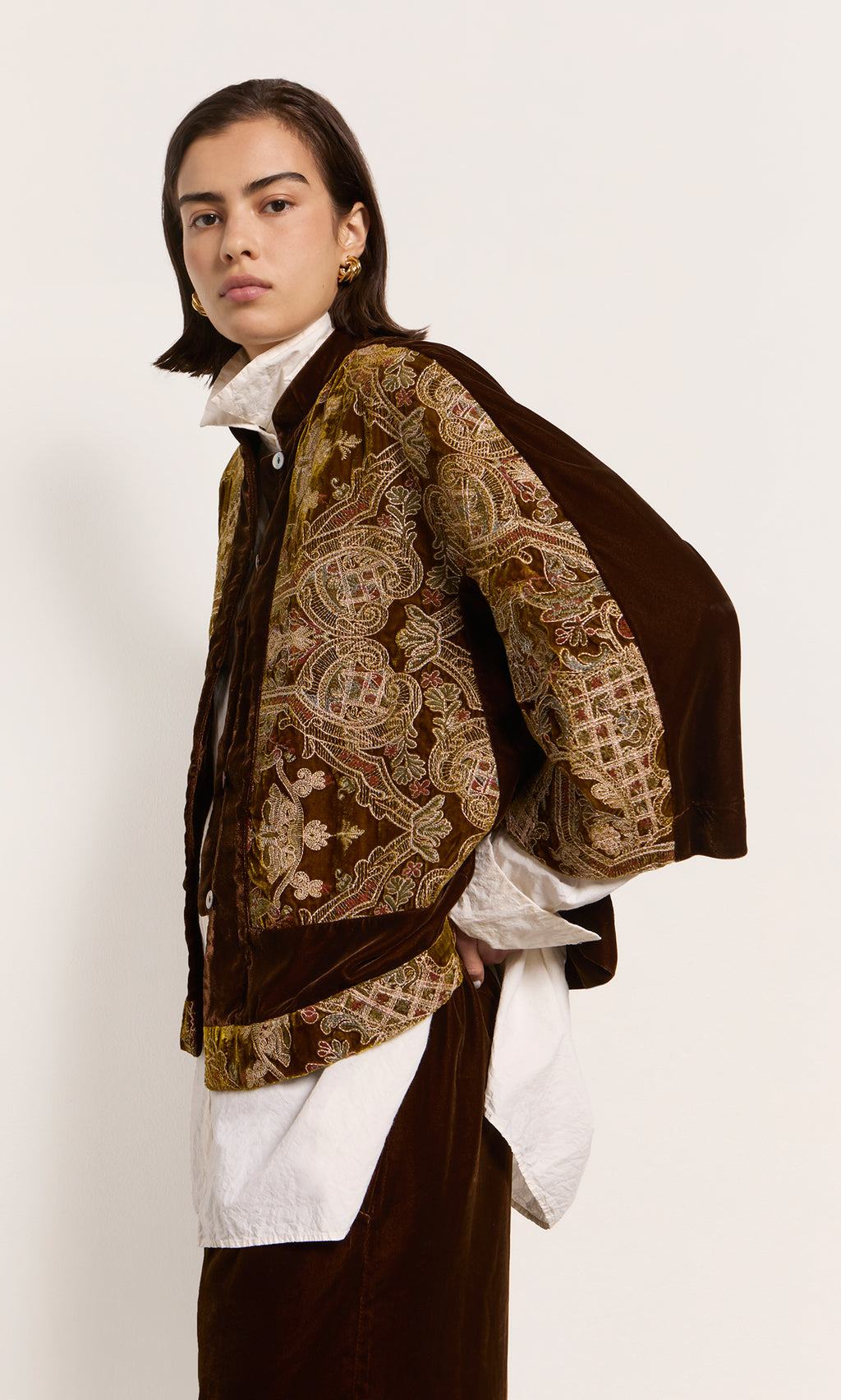 Plümo  Model in a patterned brown Kemsley Jacket with band collar over white shirt, posed sideways against plain background.