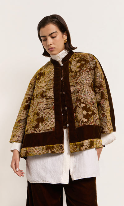 Plümo  Person wears a loose maroon Kemsley Jacket with gold embroidery over a white shirt, standing against a plain background.