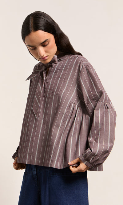 Plümo  Woman in a Kleist Blouse - Liquorice by Plümo Studio, featuring stripes, balloon sleeves, and a bow collar.