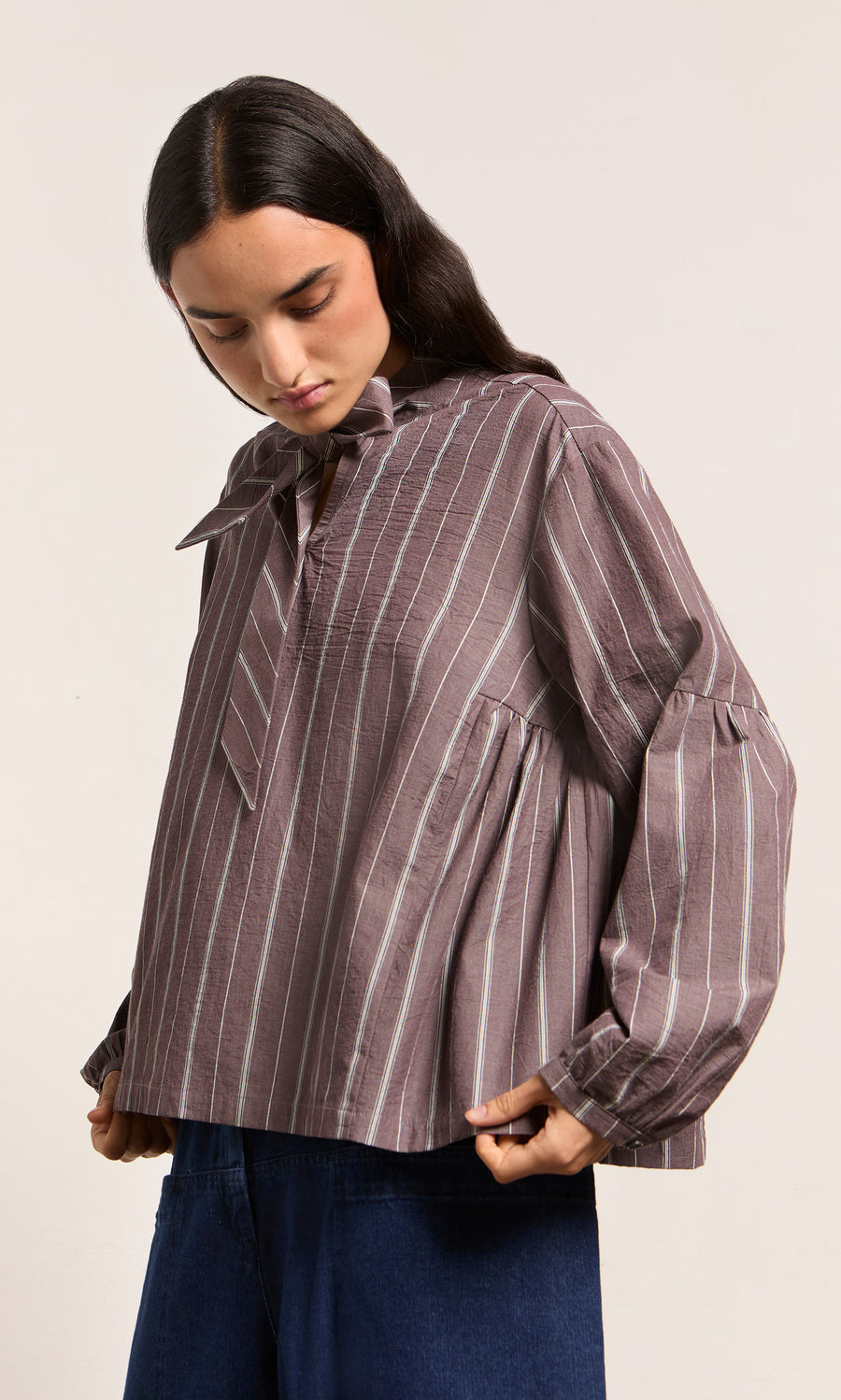 Plümo  Woman in a Kleist Blouse - Liquorice by Plümo Studio, featuring stripes, balloon sleeves, and a bow collar.