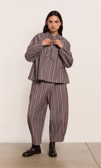 Plümo  Person in Butoni Pants - Liquorice: loose, striped cotton pants with elastic waist, styled seriously.