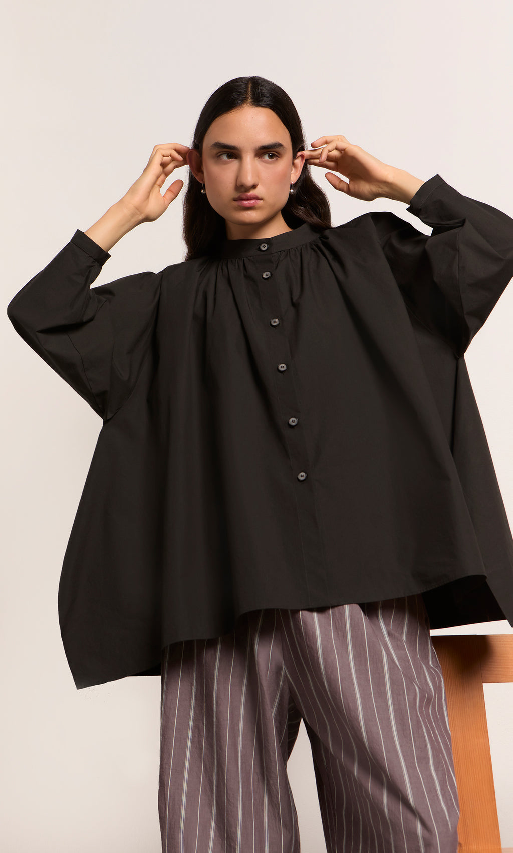 Plümo  Someone wears the Kroyer Blouse with balloon sleeves and striped pants, standing before a plain light background.