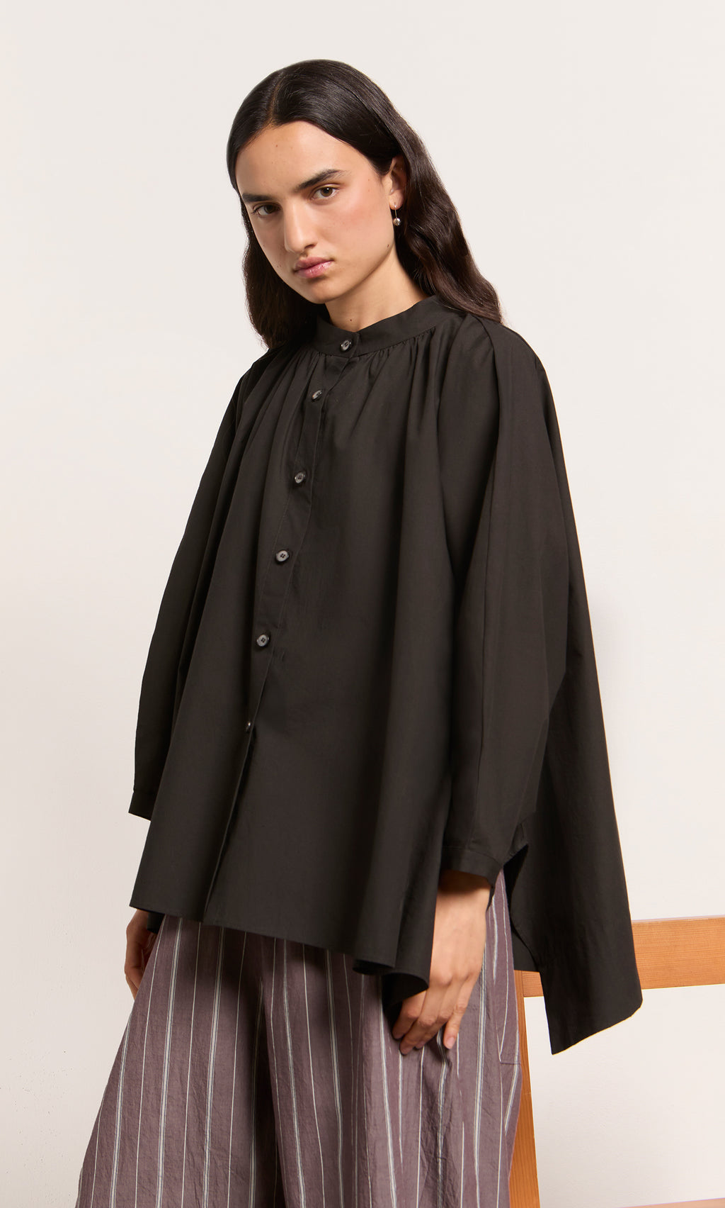 Plümo  Person in the Kroyer Blouse with striped wide-leg pants, standing against a plain background.