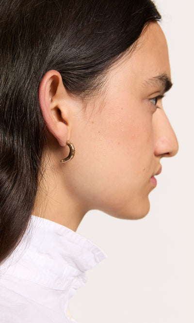 Plümo  A woman with long dark hair wears Leaping Fish Hoops and a white collared shirt, shown in profile.