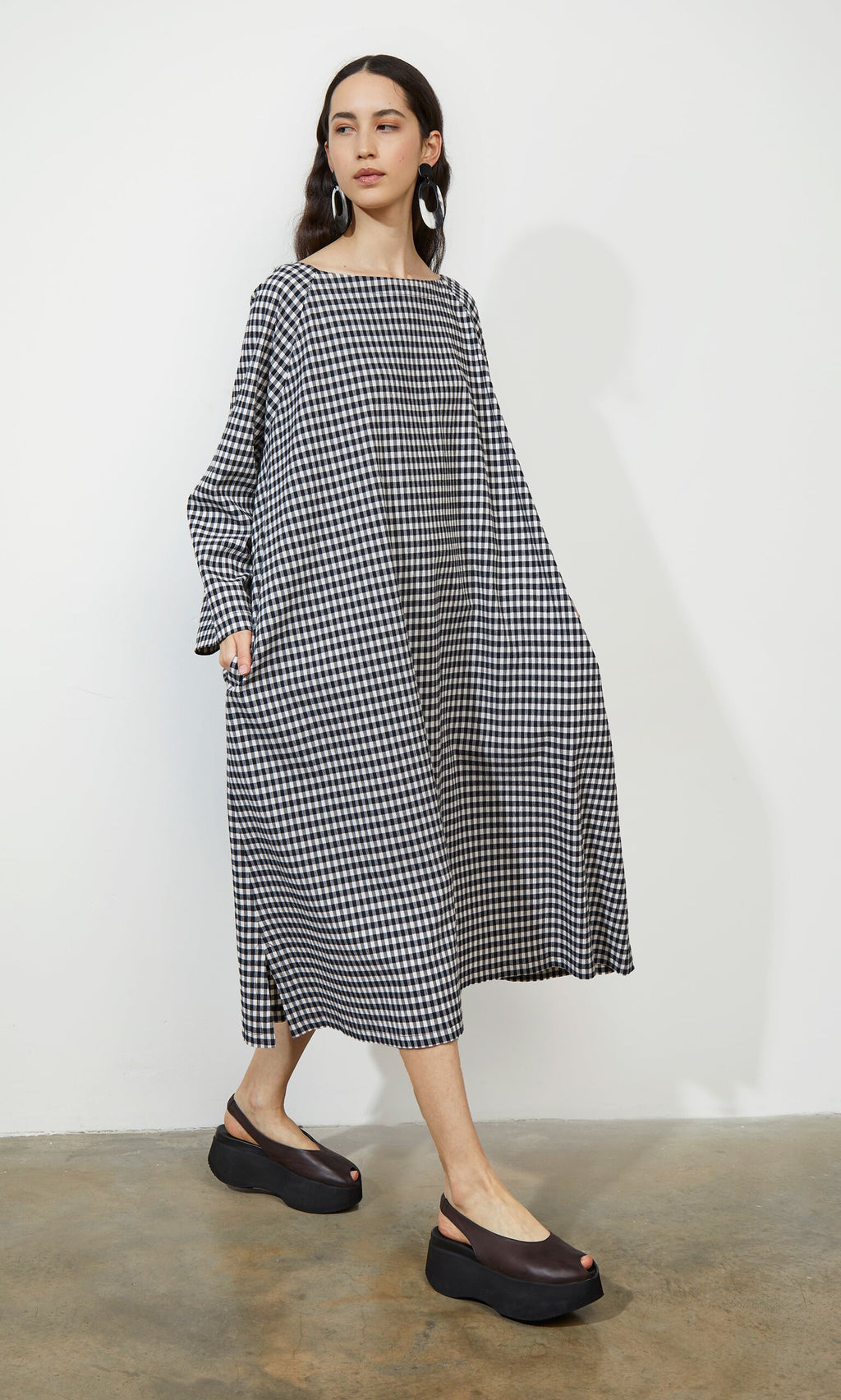 Plümo- Woman in the Marsell Dress - Gingham with a trapeze silhouette, paired with black platform sandals.