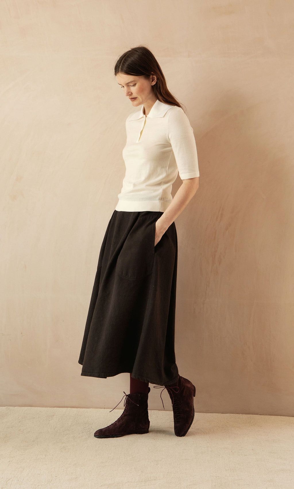 Plümo- Woman in a Merino Collar Top, black midi skirt, and dark ankle boots channels a vintage-inspired silhouette.