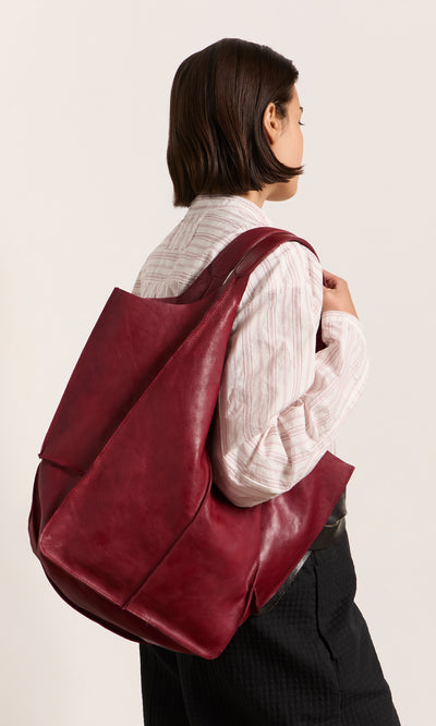 Plümo  Woman with Miller Bag - Burnt Sienna, wearing a white striped shirt and black pants.