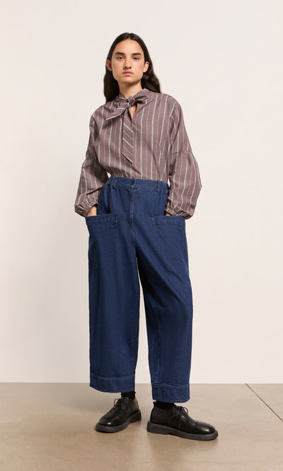 Plümo  Person in Polder Pants - Original Denim, striped blouse, and black shoes stands against a plain background.