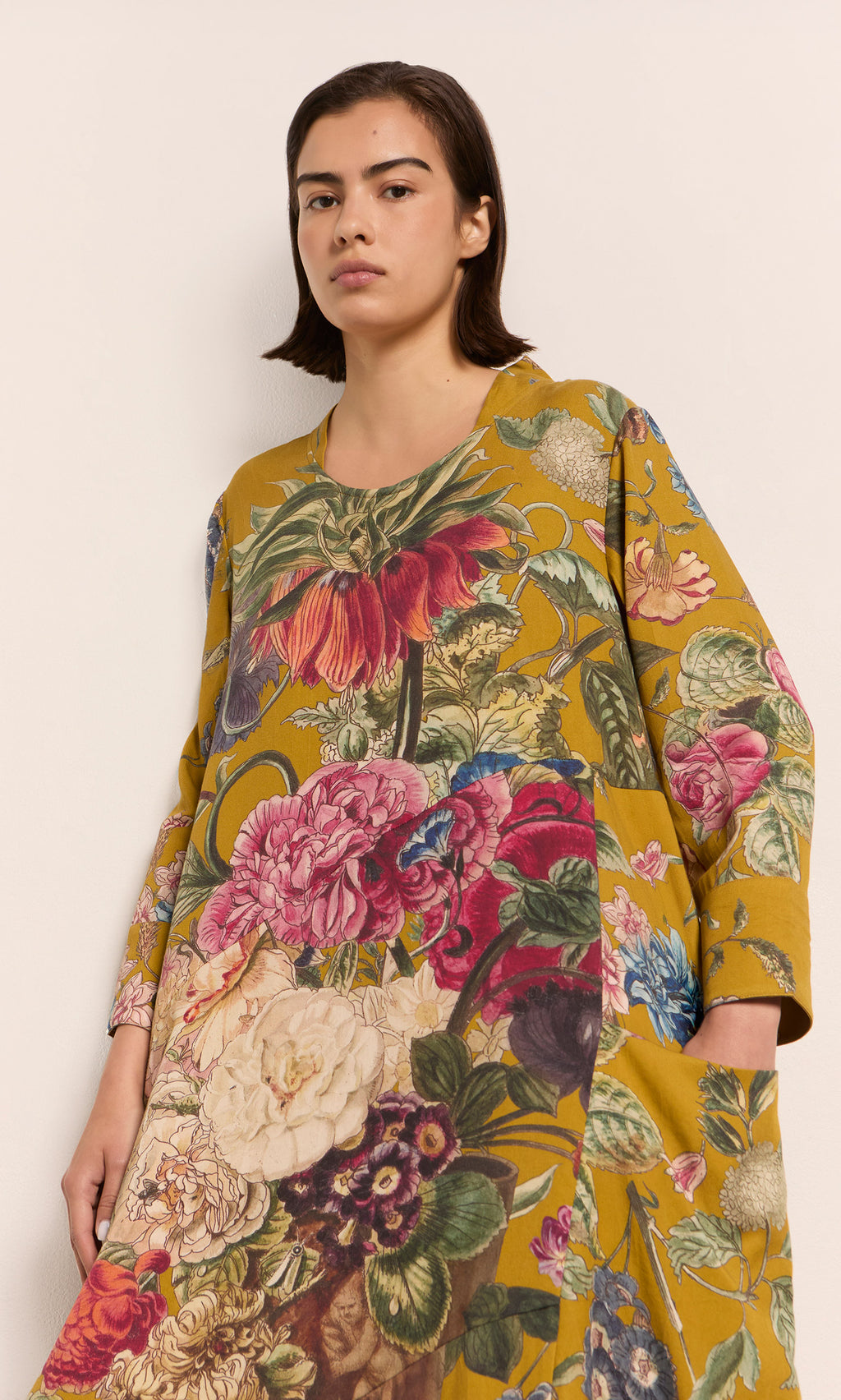 Plümo  Woman wearing the Primula Dress - Gold, a relaxed fit, long-sleeve tunic with bold floral print.