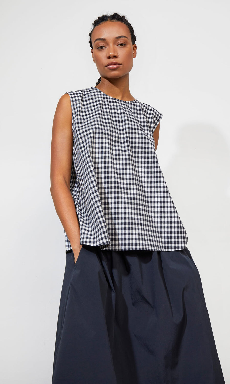 Plümo- Woman wearing the Serena Top - Gingham, paired with a navy skirt, against a plain white background.