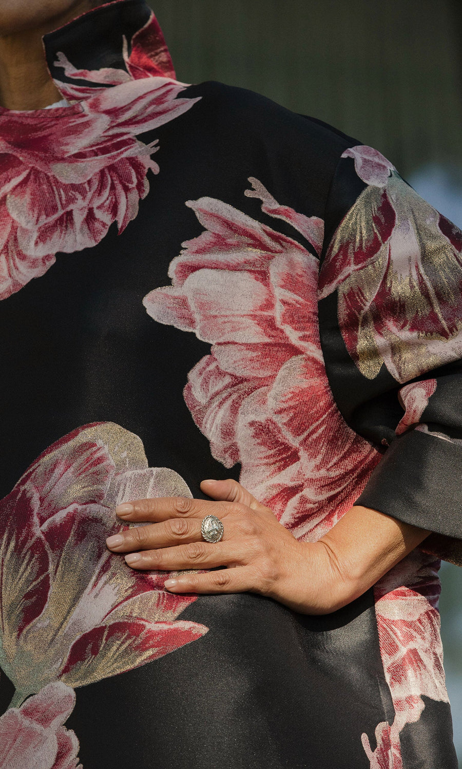 Plümo- A person in a black floral-patterned garment rests their hand on their hip, displaying the Silver Wild Ring.