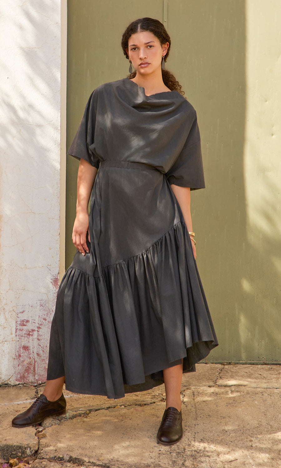 Plümo- Woman in a loose-fitting Skegg Skirt with an asymmetric hemline, standing outdoors on a sunny day.