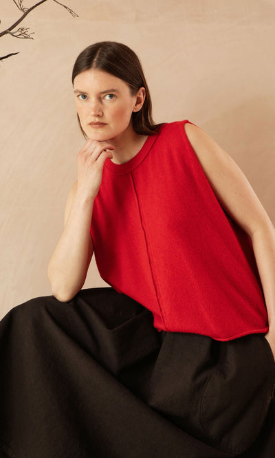 Plümo- Woman with straight brown hair wears the Stella Tank in red and a black skirt, sitting with her hand on her chin.