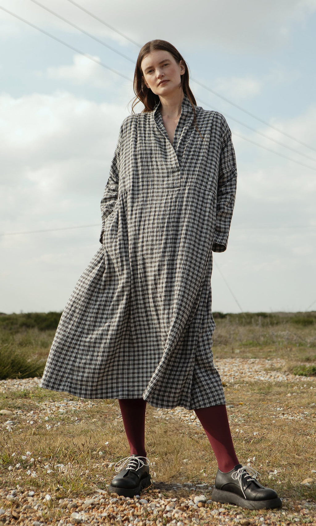 Plümo- Woman outdoors in North London, wearing the Tarkhan Dress - Plaid and burgundy tights.