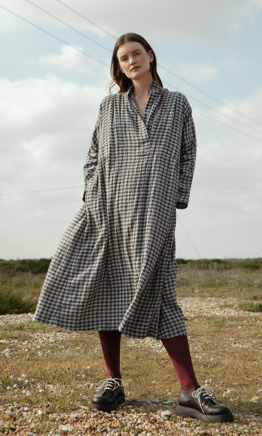 Plümo- Woman outdoors in North London, wearing the Tarkhan Dress - Plaid and burgundy tights.