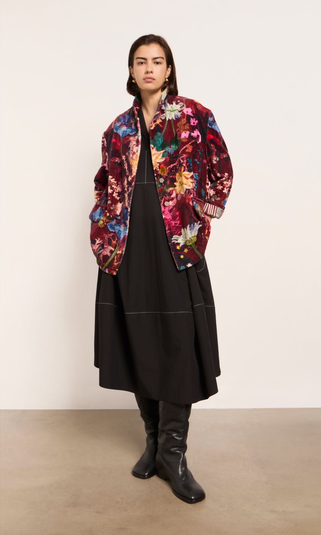 Plümo  A person wears a long black dress, black boots, and the Velvetine Blazer with floral design against a plain background.