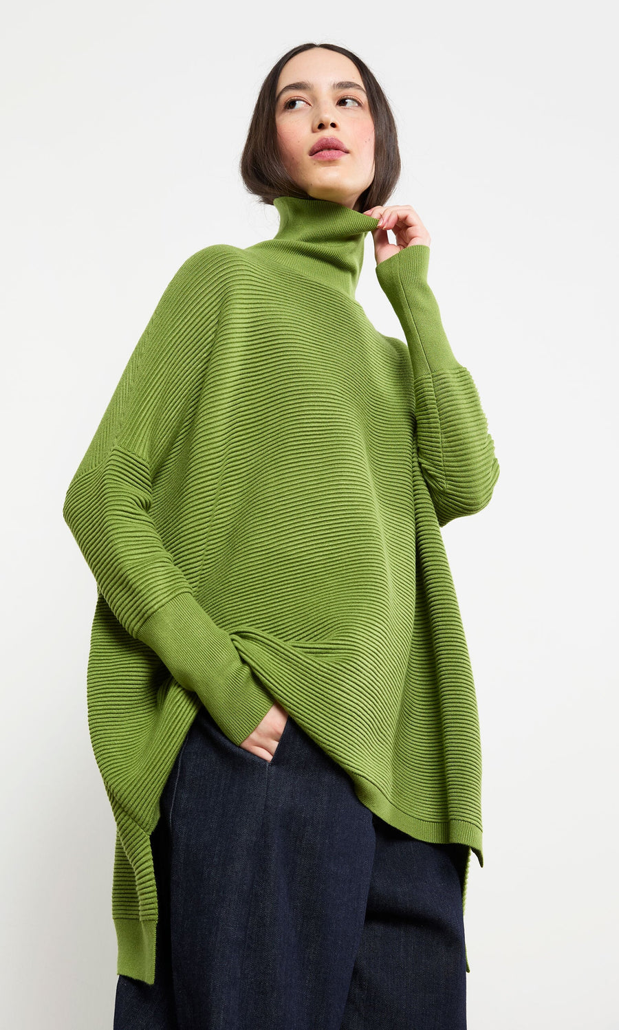 Plümo- Woman wearing the Jack Rollneck in Apple Green with dark wide-leg pants, posing against a plain white background.