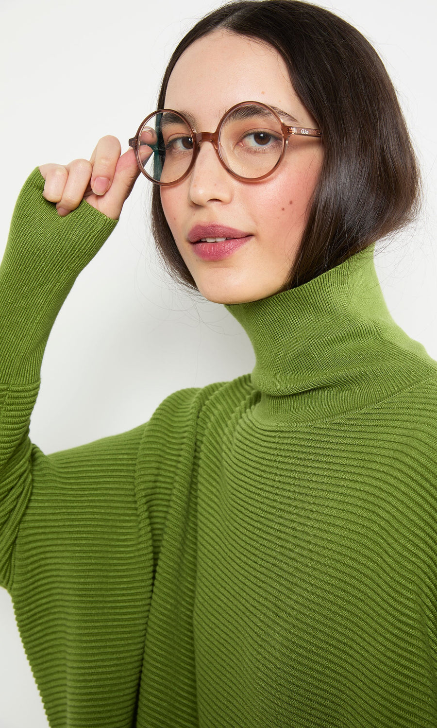 Plümo- Woman in glasses wears the Jack Rollneck in Apple Green, made from super soft yarn, smiling at the camera.