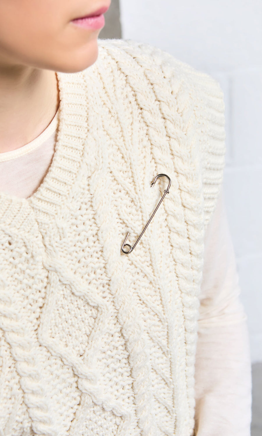 Plümo - A person wearing a cream knit sweater accessorized with a Kilt Pin attached to the front.
