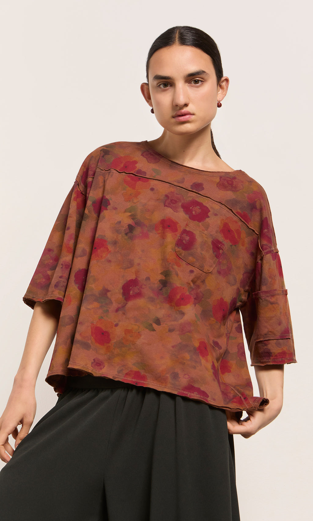 Plümo  Model wears the Angie Tee in an impressionistic floral print with black pants, posed against a plain background.