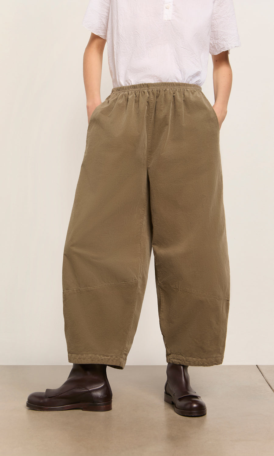 Plümo  Wearing Architect Pants- Saddle Brown with a white shirt and dark boots—sustainably made for timeless style.