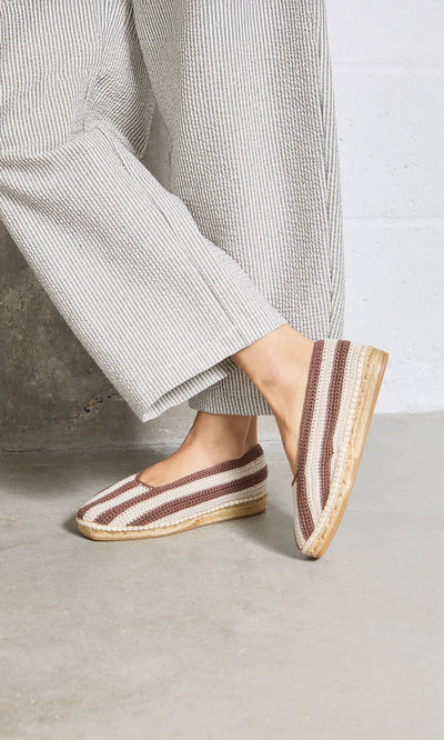 Plümo- Person wearing wide-leg striped pants and Basque Espadrilles with cushioned insoles, standing on concrete.