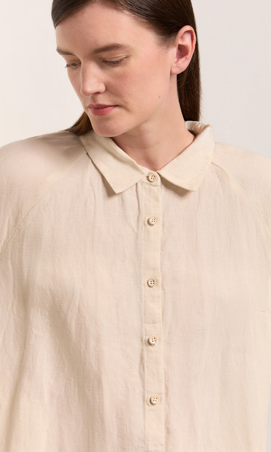 Plümo  Woman in a Beeson Shirt - Oat, with straight brown hair, channels effortless Swedish-inspired style.