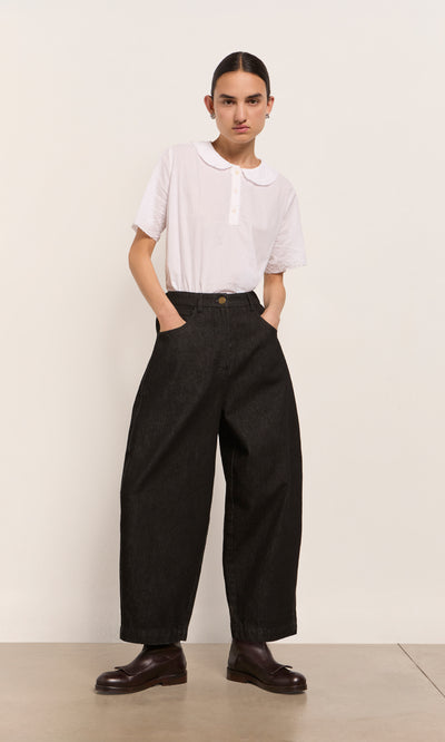 Plümo  Person in a white shirt and Black Barrel Pants stands against a plain background.