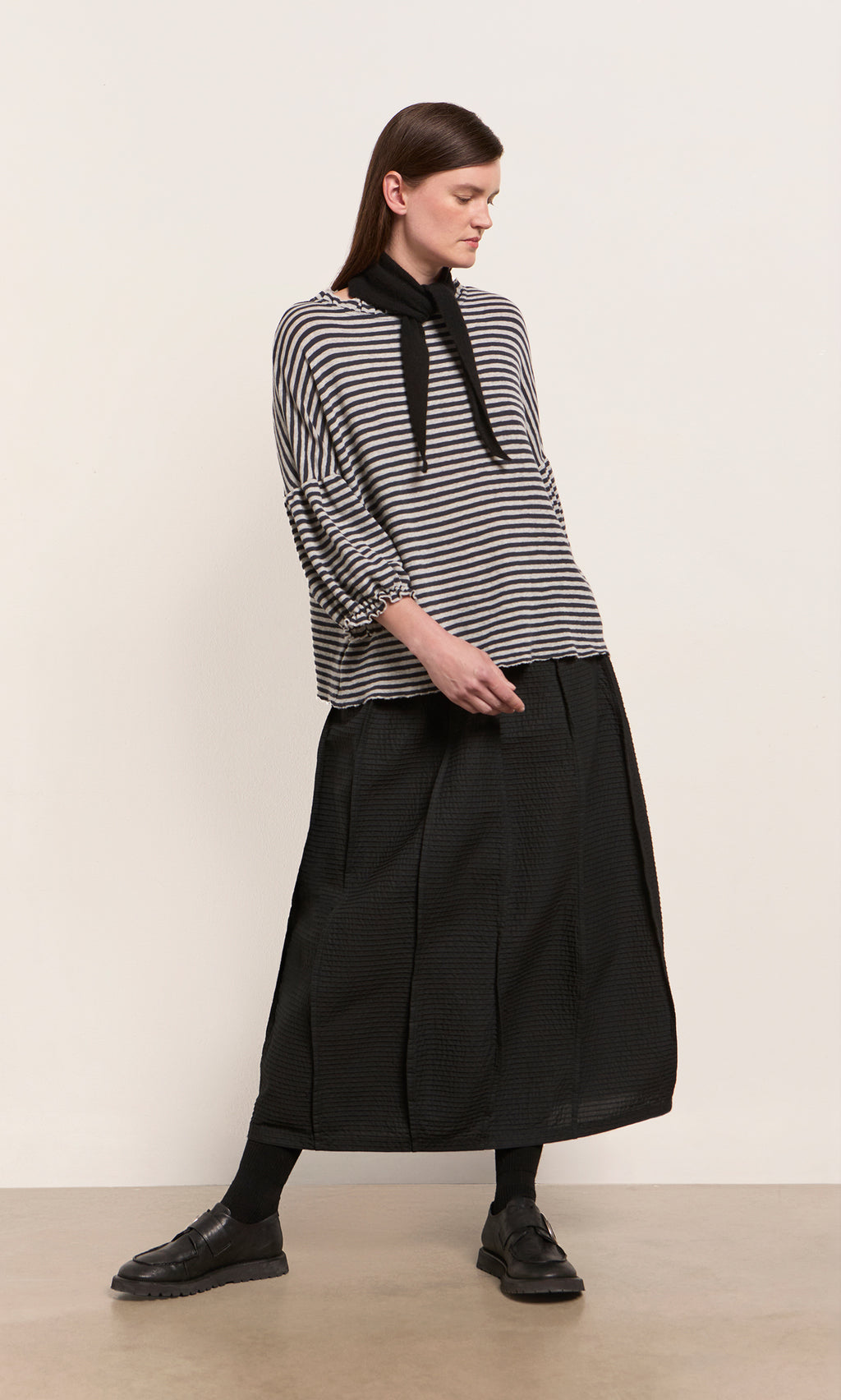 Plümo  Woman in a striped top and black skirt styles her look with a Black Cashmere Necktie for a touch of Danish flair.