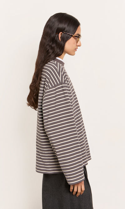 Plümo  Person with long dark hair and glasses models the Breton Tee - Coal in profile against a light background.
