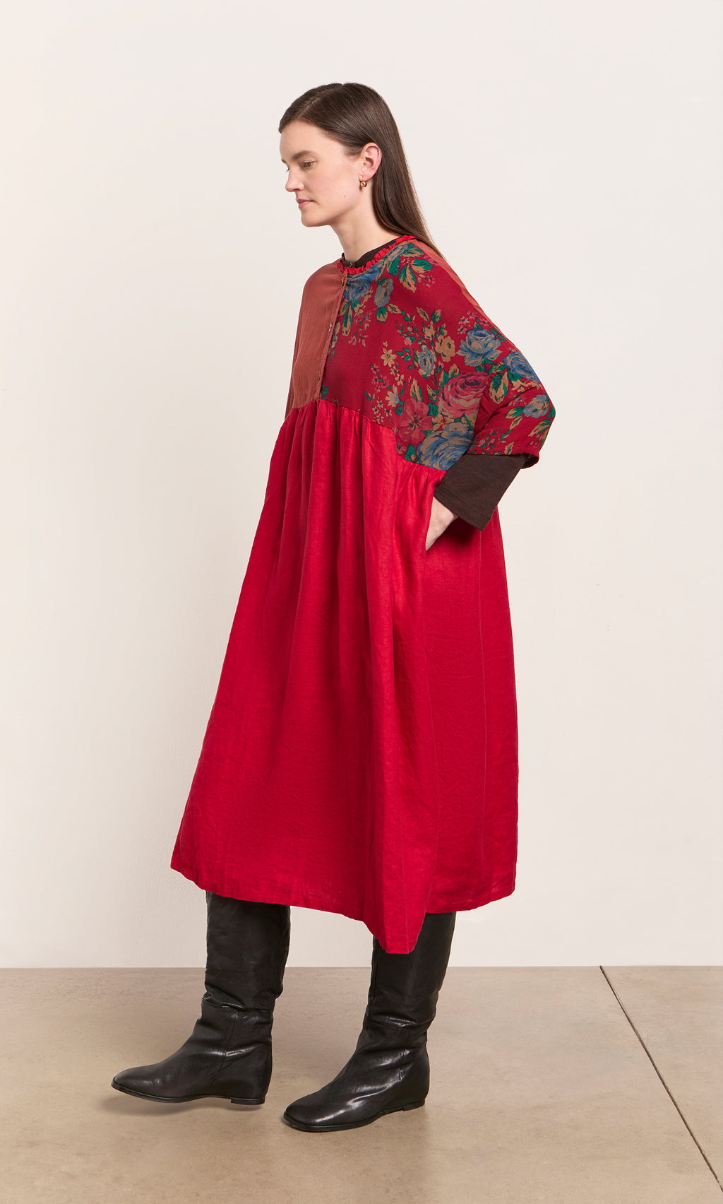 Plümo  Woman in a red Burns Patchwork Dress with floral top, black boots, standing sideways against a plain background.