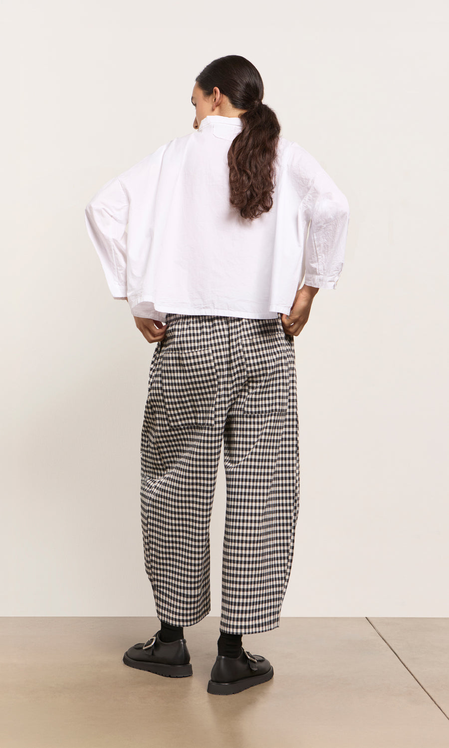 Plümo  A woman faces away, wearing a white shirt and Butoni Pants - Black and White with black shoes.
