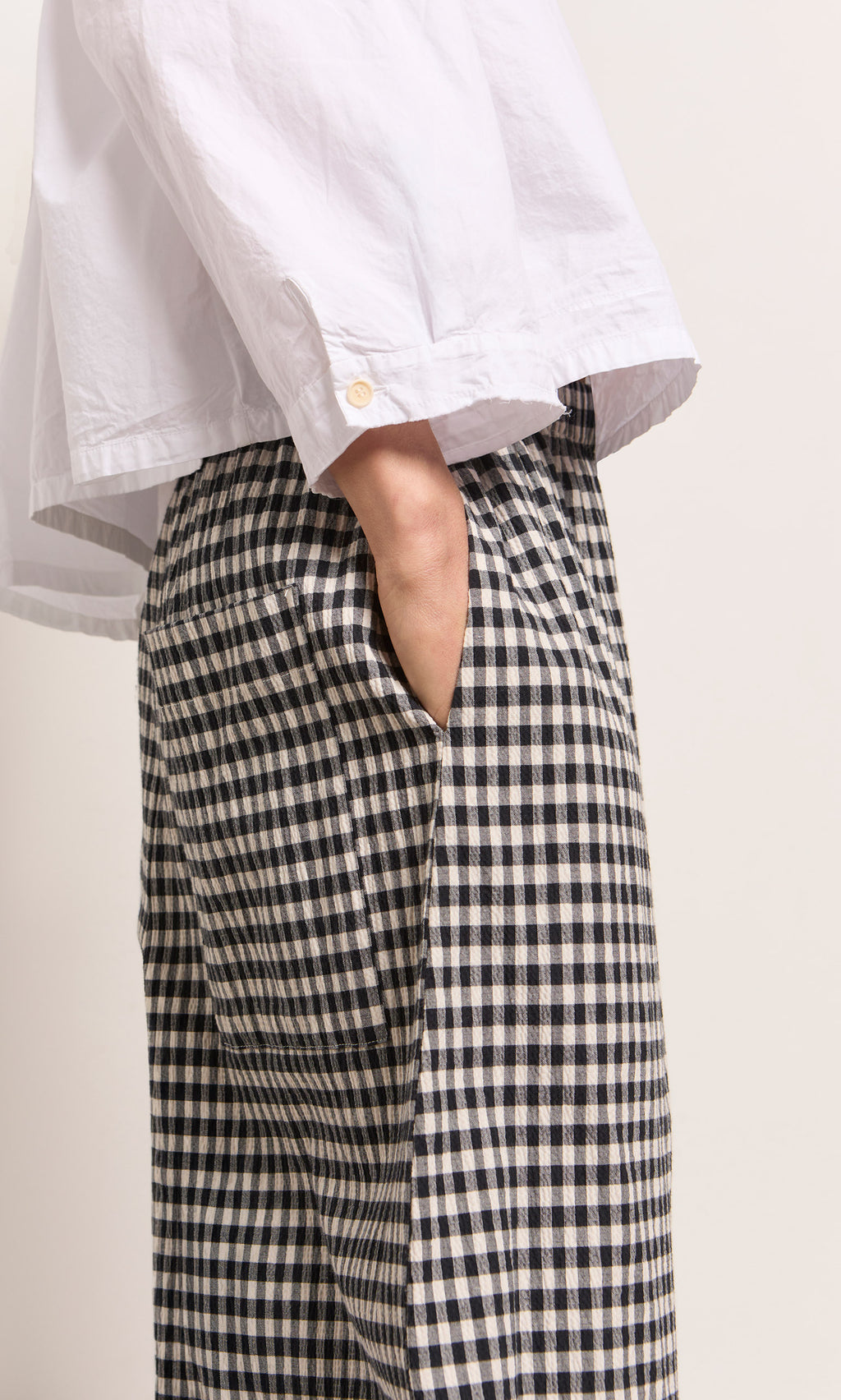 Plümo  Person wears a white shirt and Butoni Pants - Black and White, hand casually tucked in their pocket.