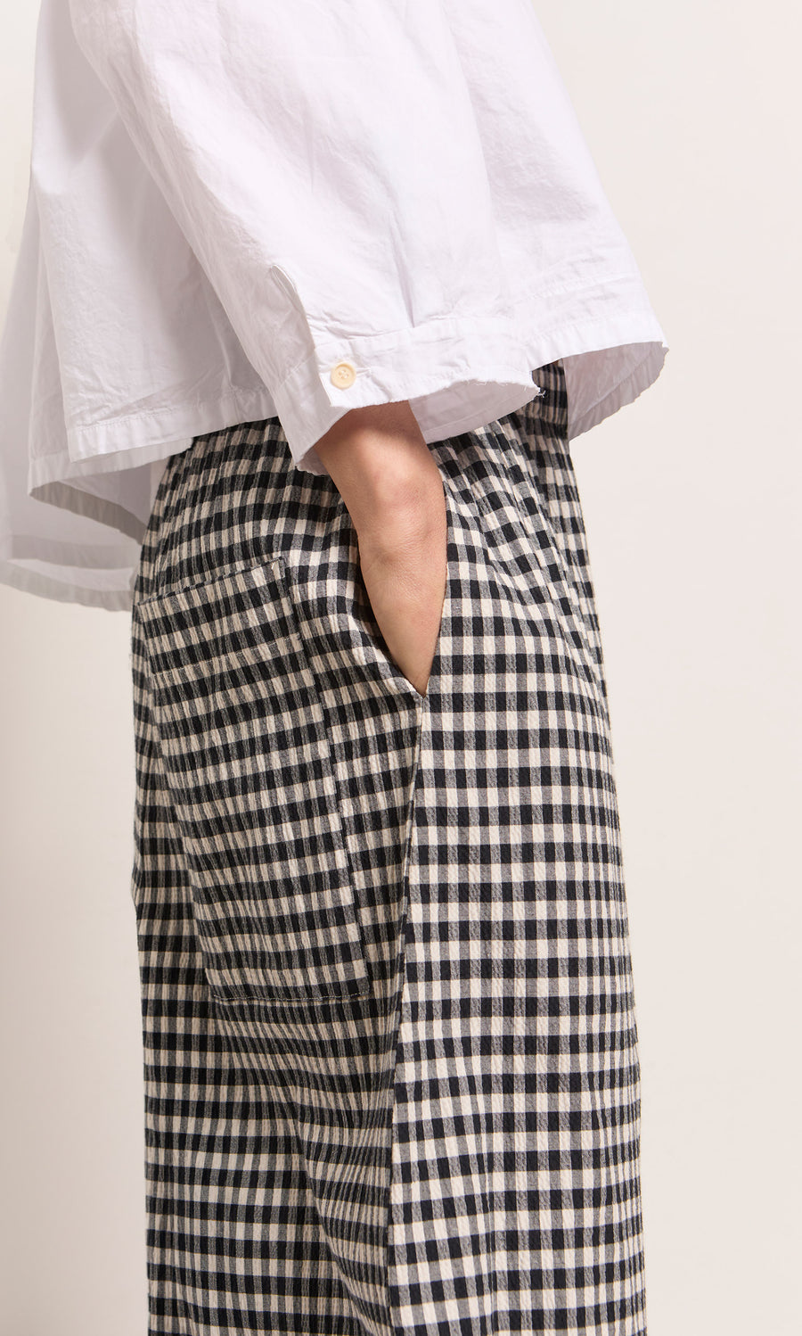 Plümo  Person wears a white shirt and Butoni Pants - Black and White, hand casually tucked in their pocket.