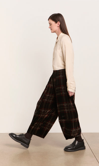 Plümo  Person in a beige shirt and Carson Tartan Pants walks indoors, right profile visible, against plain background.