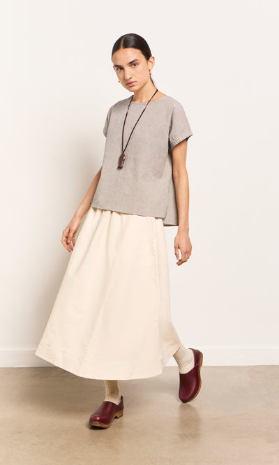 Plümo  Person in gray top, cream maxi skirt, red clogs, and Yumi Fish Necklace stands against a plain background.