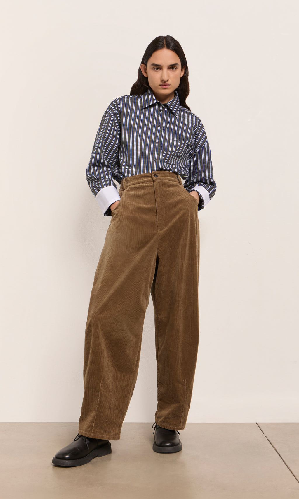Plümo  Person wears a striped shirt, Breda Pants, and black shoes against a plain light background.