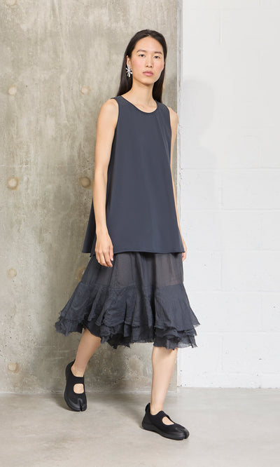 Plümo- Woman in the Edel Top and A-line black tulle skirt stands by a concrete wall in relaxed fit attire.