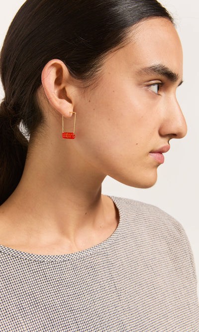Plümo- Person with dark hair in a low ponytail wears Fortuna Earrings - Satsuma, shown in profile against a plain background.